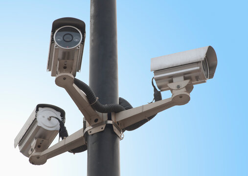 A metal post with a gantry and traffic cameras facing in three different directions monitoring traffic flow.