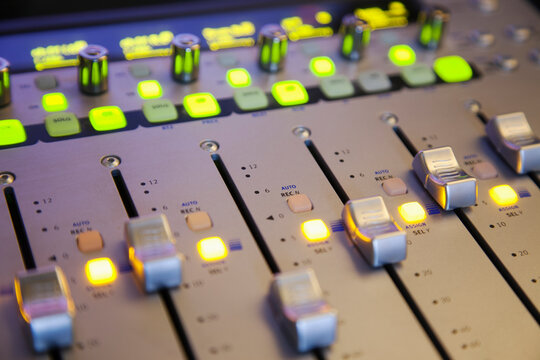 A sound board with lighted controls in a home recording studio