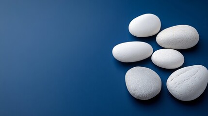 Several smooth white stones are arranged on a blue surface
