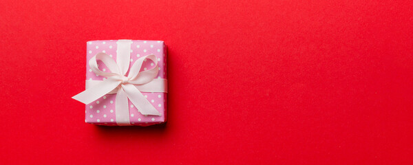 Valentine day composition: red gift box with bow and heart. Christmas present. View from above....