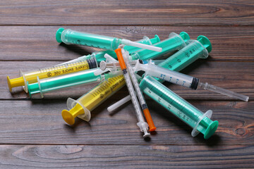 Top view of a pile of syringes and insulin syringes ready for injection at wooden background....
