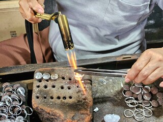 Close-up of a craftsman heating a silver ring during the jewelry making process