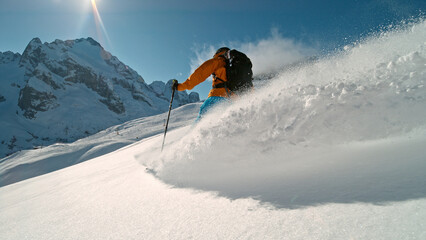 Skier riding in the scenic Alps mountains in fresh powder snow , beautiful sunny day