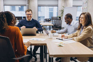 Professional team collaborating during strategic planning session, diverse colleagues brainstorming project details in modern workplace setting