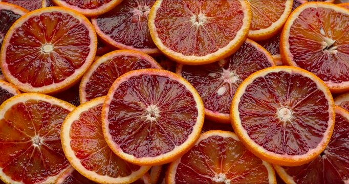 Unpeeled, sliced Sicilian oranges background. Table spin.
