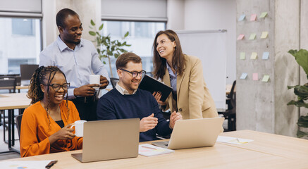 Professional team collaborating, sharing insights across laptops, representing multicultural workplace dynamics with energy and connectivity