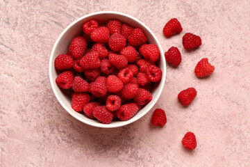 Bowl with fresh raspberries on pink background