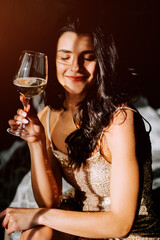 Young woman in elegant dress enjoys a glass of sparkling wine in a dimly lit setting during an evening gathering