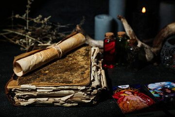 Witch's magic attributes with book and tarot cards on dark table, closeup