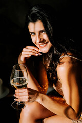 Woman enjoying a glass of white wine while sitting gracefully in a dimly lit venue