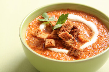 Bowl of tasty cream soup with croutons on green background