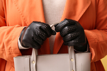 Woman in black leather gloves holding stylish handbag, closeup