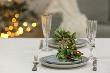 Beautiful table setting with mistletoe for Christmas dinner in living room