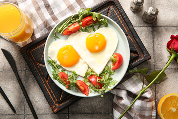Composition with tasty fried eggs, tomatoes and glass of juice on grey tile background