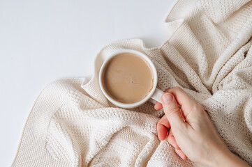A cup of coffee with a warm blanket, offering a cozy and relaxing atmosphere. Perfect for themes of comfort