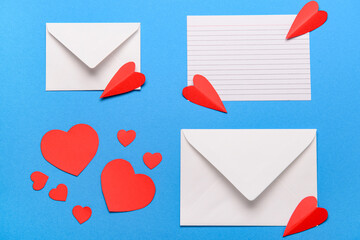 Envelopes with blank card and red paper hearts on blue background. Valentine's Day celebration