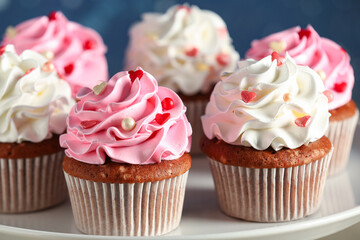 Stand with tasty cupcakes for Valentine's Day on blue background, closeup