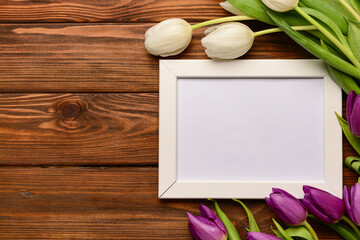 White frame with purple and white tulips on wooden background