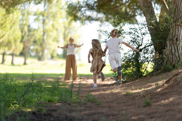 Children running towards parent in sunny forest