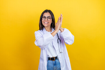 Young brunette doctor woman wearing stethoscope standing over isolated yellow background clapping and applauding happy and joyful, smiling proud hands together