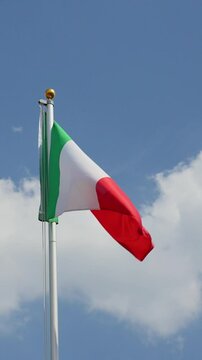 Waving Italy flag flying on a flagpole, vertical video, low angle