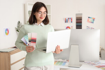 Beautiful interior designer with laptop and color palettes in office