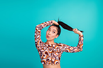 Photo of lovely young lady pull hair ponytail look empty space amazed dressed stylish colorful...