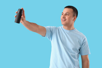Fototapeta premium Handsome young man with deodorant on blue background