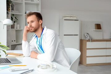Tired medical intern sitting at table in clinic