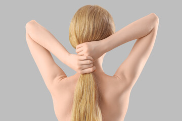 Beautiful young woman with naked back on grey background