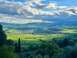 Stunning spring day in Pienza, Italy, overlooking lush Tuscan hills. Vibrant greens, dramatic...