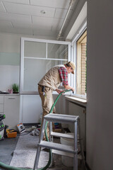 Fototapeta premium Carpenter installing a new window in a family house during renovation and refurbishment.