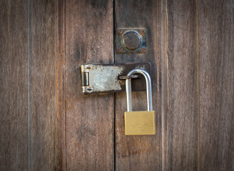 Locked padlock with chain at brown wooden door background, vintage