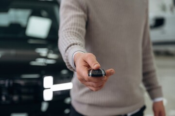 Keys for new automobile. Man is with the car in dealership