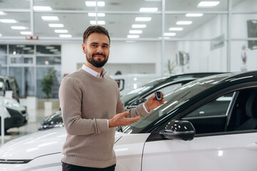 Keys for new automobile. Man is with the car in dealership