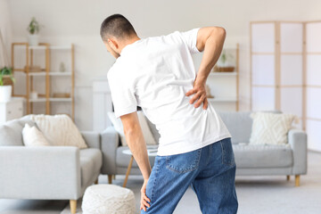 Young man suffering from back pain at home