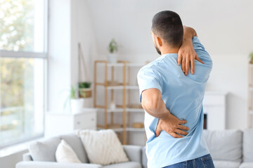 Young man suffering from back pain at home