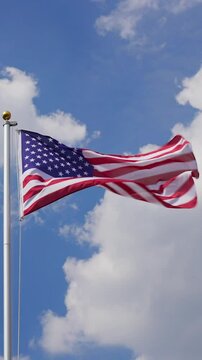 Waving USA flag flying on a flagpole, vertical video, medium shot, low angle