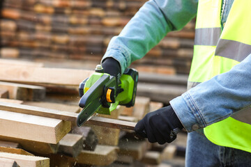 Male carpenter sawing plank at sawmill, closeup