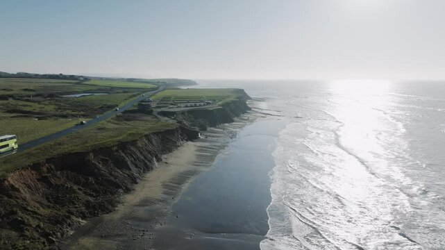 A beautiful beach with a cliff in the background. The water is calm and the sky is clear