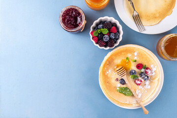 Traditional Maslenitsa food, Eastern European Slavic thin pancakes crepes, with various sweet spreads, toppings and fillings - honey, berries, jams 