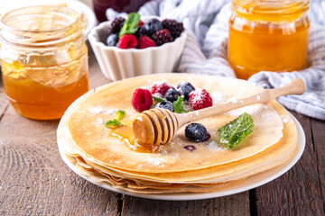 Traditional Maslenitsa food, Eastern European Slavic thin pancakes crepes, with various sweet spreads, toppings and fillings - honey, berries, jams 