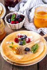 Traditional Maslenitsa food, Eastern European Slavic thin pancakes crepes, with various sweet spreads, toppings and fillings - honey, berries, jams 