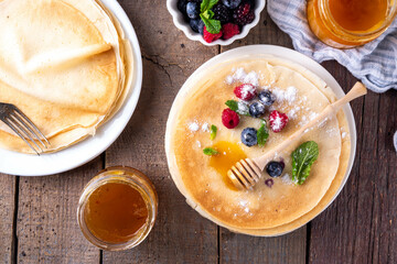 Traditional Maslenitsa food, Eastern European Slavic thin pancakes crepes, with various sweet spreads, toppings and fillings - honey, berries, jams 