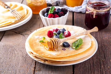 Traditional Maslenitsa food, Eastern European Slavic thin pancakes crepes, with various sweet spreads, toppings and fillings - honey, berries, jams 