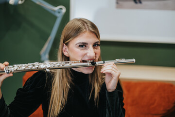 Young woman playfully engaging with a musical flute indoors, showing a light hearted moment. The...