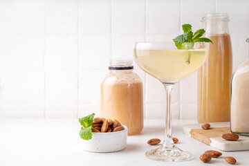 Sweet and sour lemon orgeat cocktail, Orgeat Lemonade Recipe, one martini glass with alcohol boozy drink and almond orgeat syrup bottle