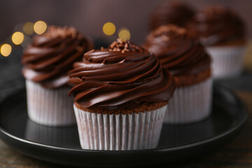 Tasty cupcakes with chocolate cream on wooden table, closeup