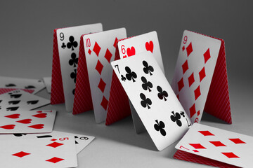 Collapsed house of playing cards on grey background, closeup