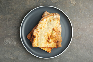 Halves of tasty calzone on grey textured table, top view
